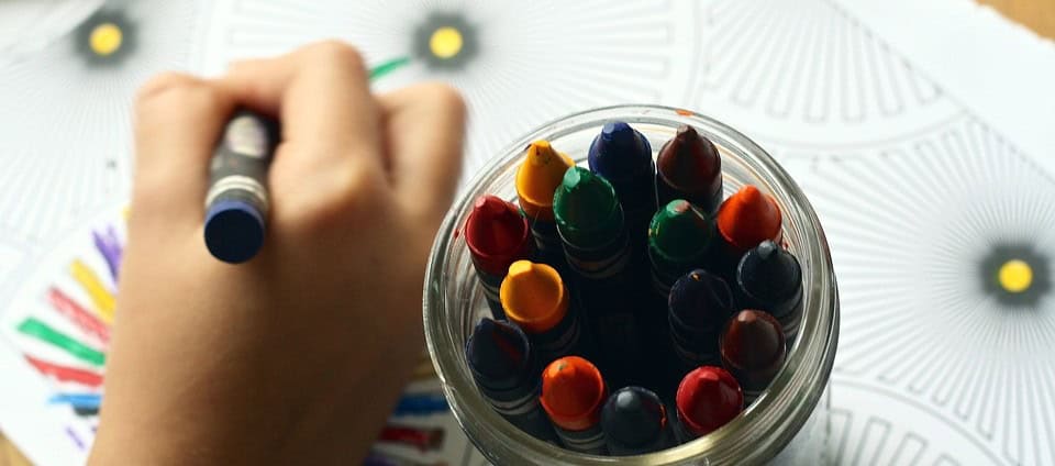 Vibrant marker caps in a glass jar on a colorful, patterned surface, emphasizing safety tips for kids and creative activities promoted by the "Don't Stick Don't Stuff" educational book.