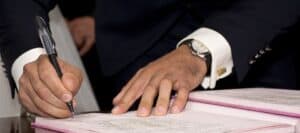 Signing a legal document with a pen, business attire, professional setting, safety and security, importance of careful signing, formal documentation.