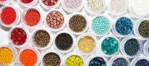 Colorful craft beads organized in small plastic containers for kids' safety and creativity. Perfect for children's craft projects, emphasizing brain safety and fun learning activities.