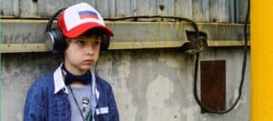 Kid listening to headphones against urban background promoting safety awareness for children at risk of accidental injuries from electrical hazards and unsafe environments.