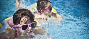 Children wearing sunglasses swimming in a pool to promote water safety and awareness from the "Don’t Stick Don’t Stuff" safety book.