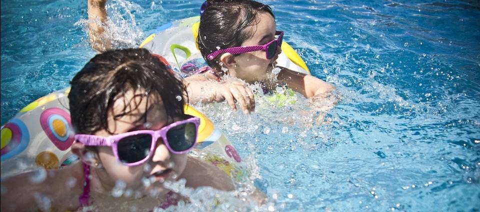 Children wearing sunglasses swimming in a pool to promote water safety and awareness from the "Don’t Stick Don’t Stuff" safety book.