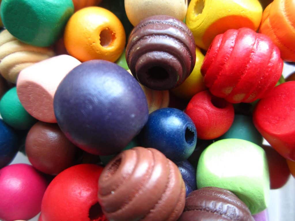 Colorful wooden beads in various shapes and sizes, used for children's crafts and learning activities. Bright and vibrant, these beads promote sensory development and safety education through playful engagement.